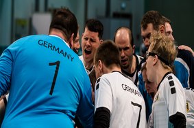 Deutsche Unified Handball Athleten motivieren sich im Mannschaftskreis. Sie tragen weiße (Feldspieler) oder blaue (Torhüter) Trikots.